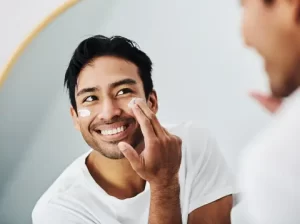 A man smiling at his reflection in the mirror. -men 
